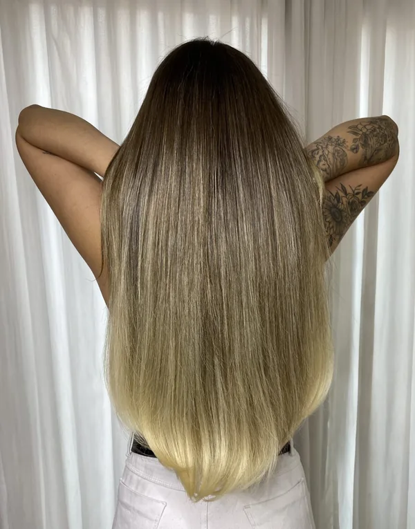 Cabelo liso com raiz escura e pontas loiras até a altura do quadril, vista de costas