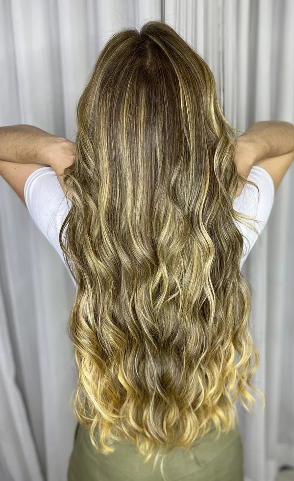 Cabelo ondulado com mechas claras até a altura do quadril, vista de costas